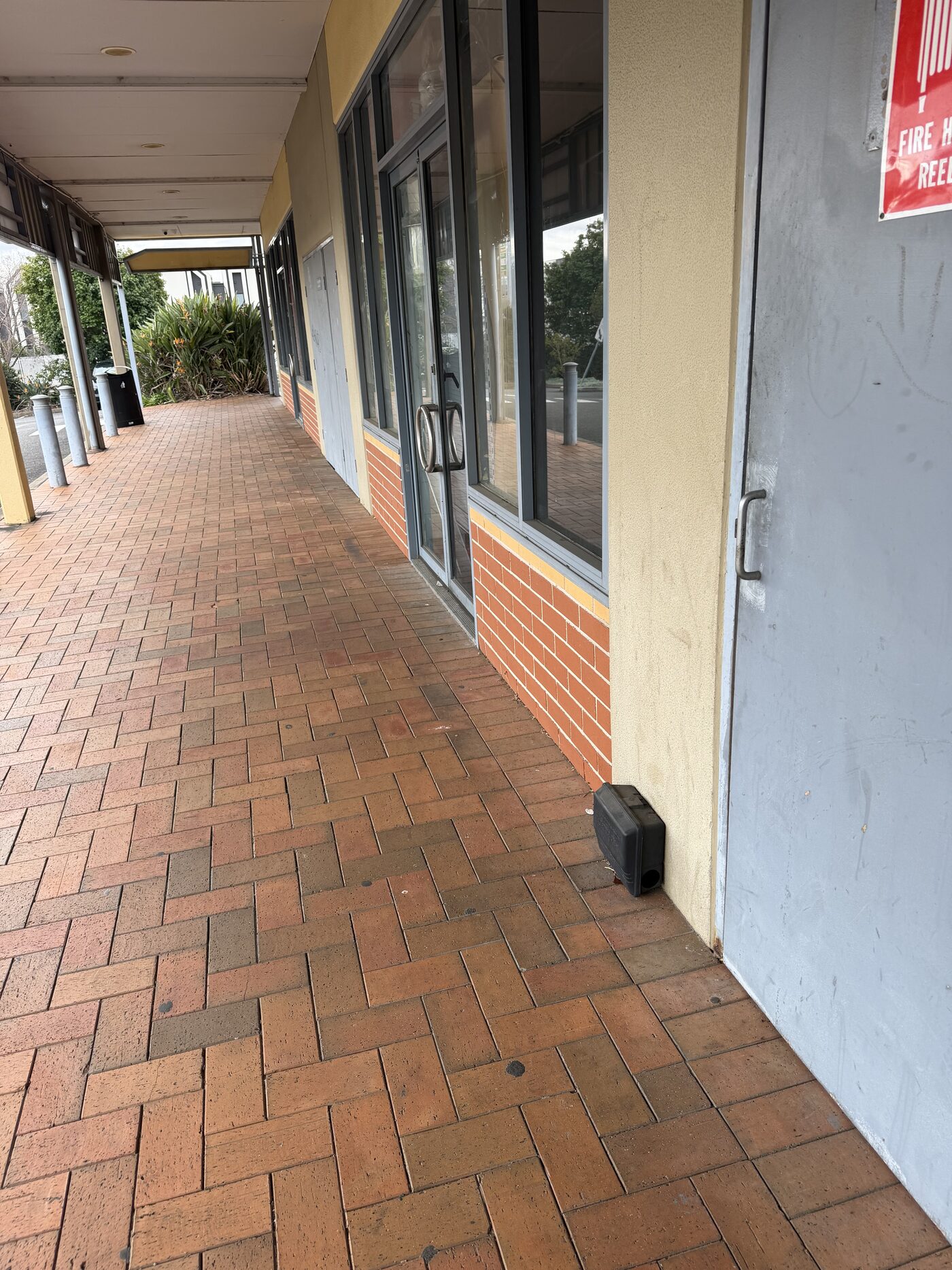 Doctor Pesty rodent bait station installed at a commercial shopping strip entrance